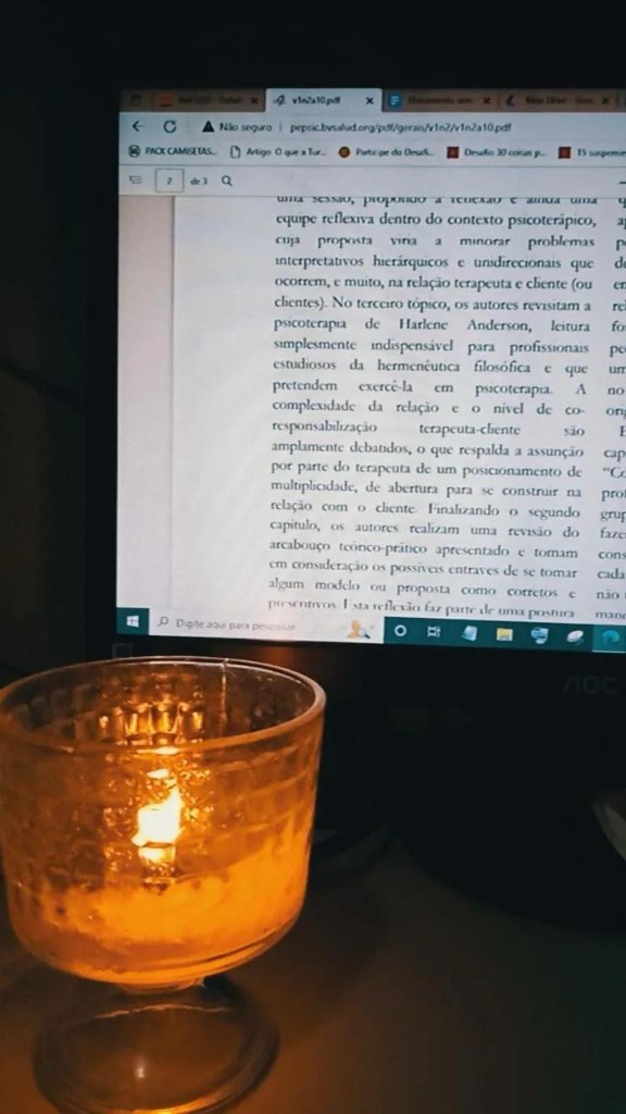 Livros de psicologia e vela acesa ao lado do monitor
